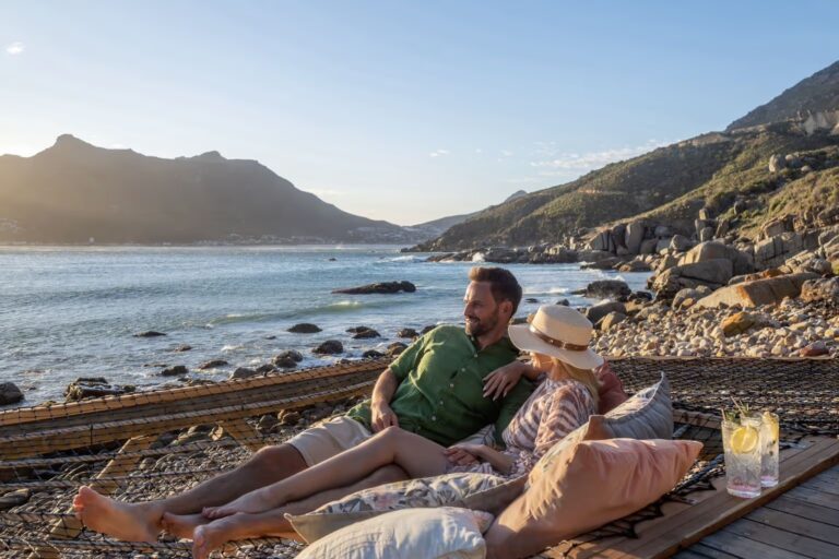 Couple resting on the deck by the water, Tintswalo Lodges