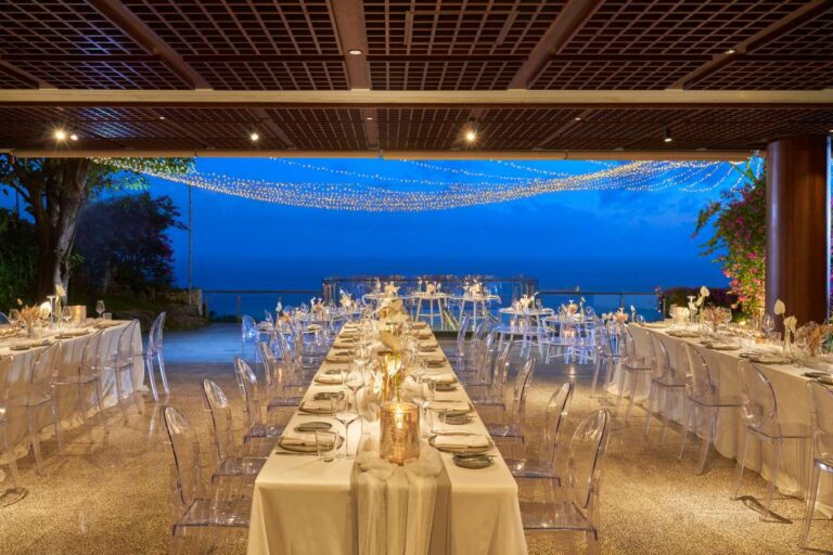 A long dinner table laid at dusk at Tirtha Uluwatu, Tirtha Bridal