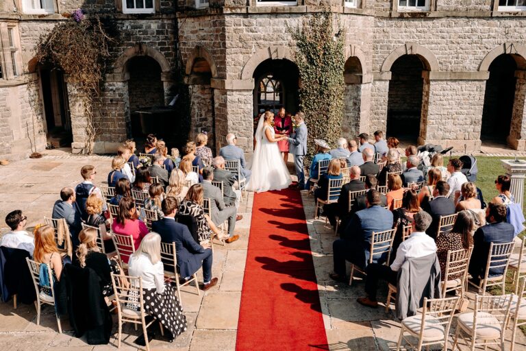 Red-carpet aisle ceremony under the arcade, Tissington Hall