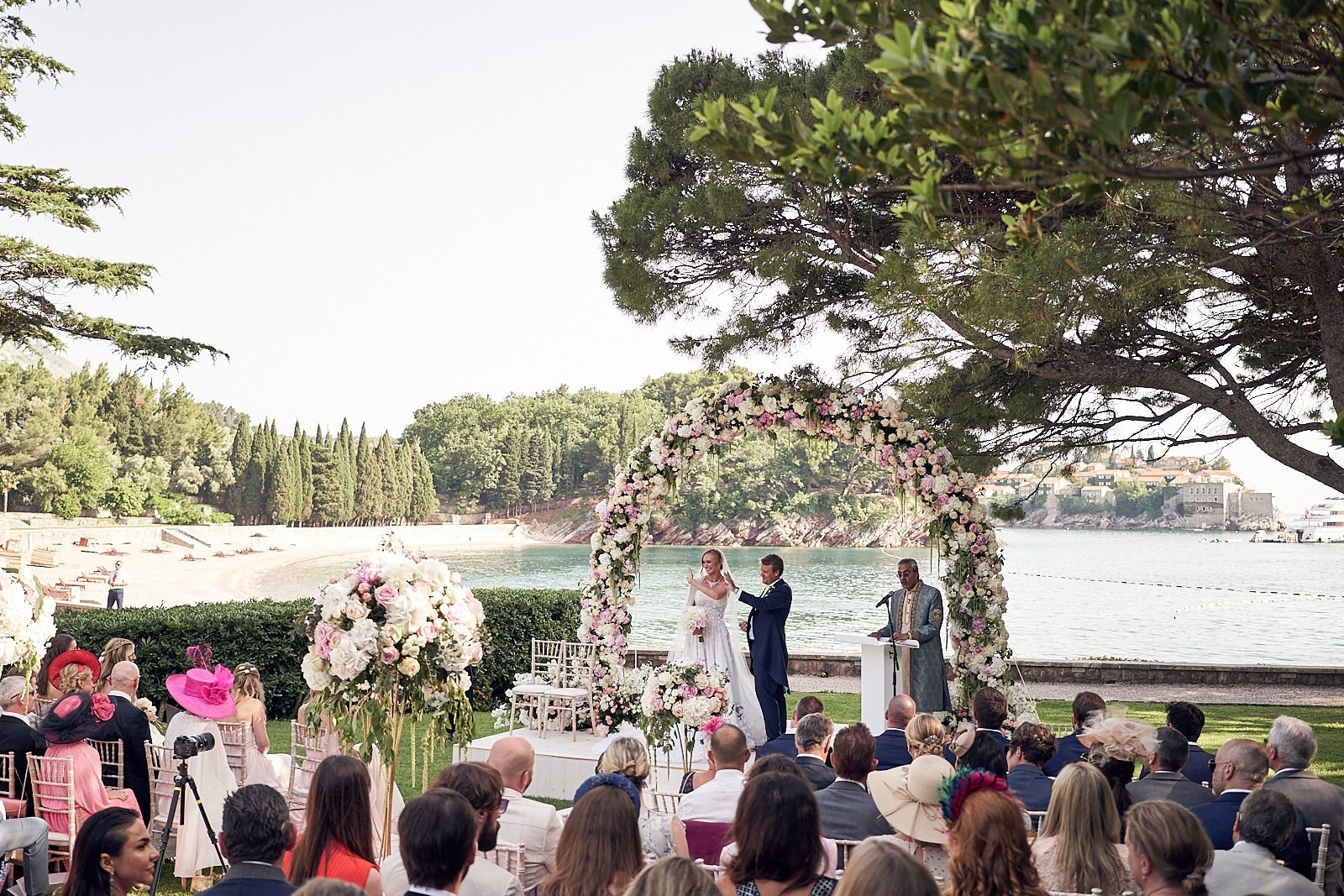 Floral arch ceremony beside the sea with guests seated, Tobi Tobi