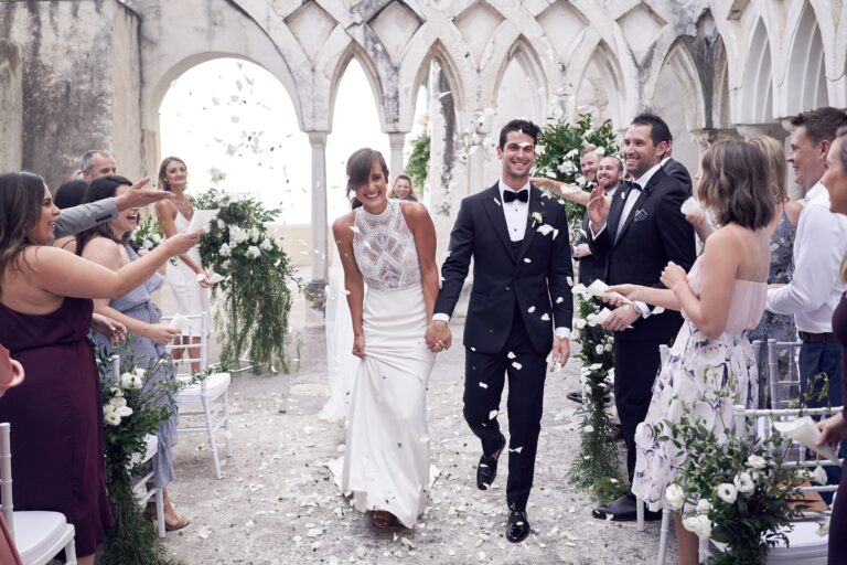 Newlyweds leave a cloister ceremony as guests throw petals, Tobi Tobi