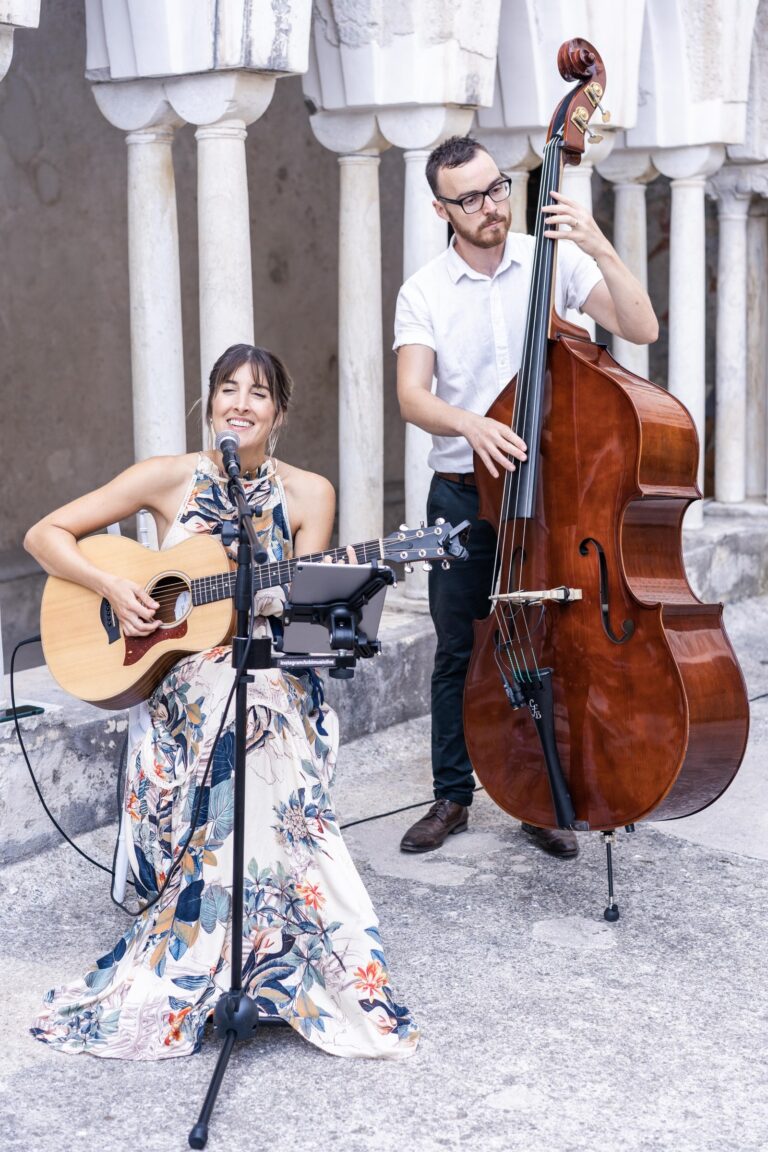 Duo playing beside a white arcade in a cloister, Tobi Tobi