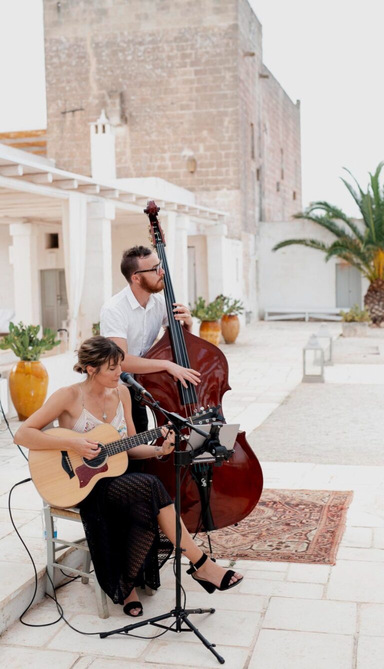 Duo playing on a patterned rug in a white-walled courtyard, Tobi Tobi