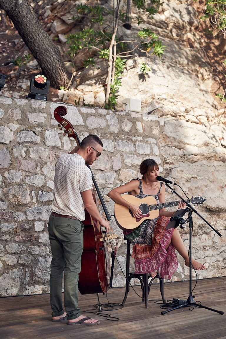 Duo performing on a timber stage against a stone wall, Tobi Tobi