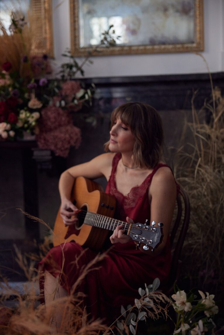 Renee on acoustic guitar among dried flowers and candlelight, Tobi Tobi