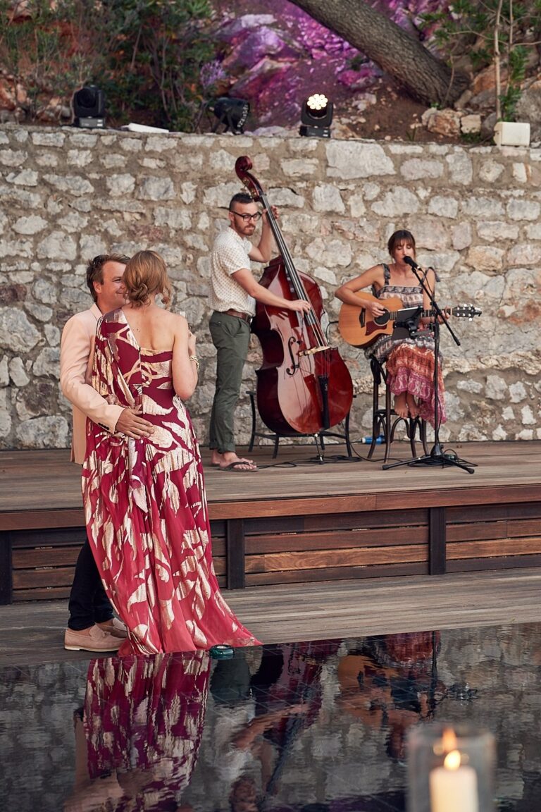 Guests dancing in front of the duo on a stage beside a stone wall, Tobi Tobi