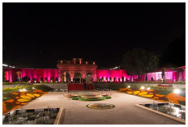 A palace lit for a night wedding, floral rangoli patterned across the lawn, Tomas De Bruyne