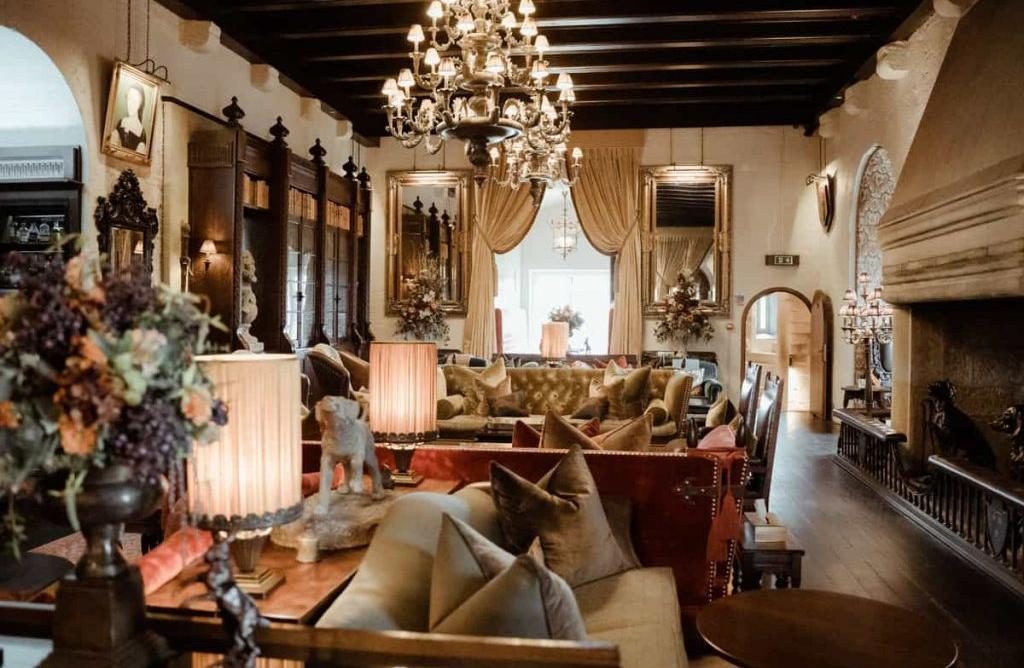 A panelled sitting room with a chandelier, armchairs and an open fireplace