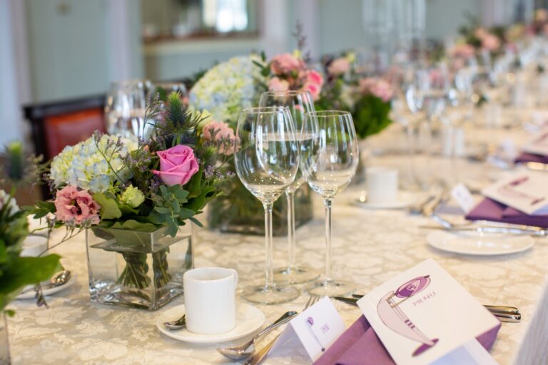 Table flowers, glassware and illustrated menus on a long table in the Library, Trinity House on Tower Hill