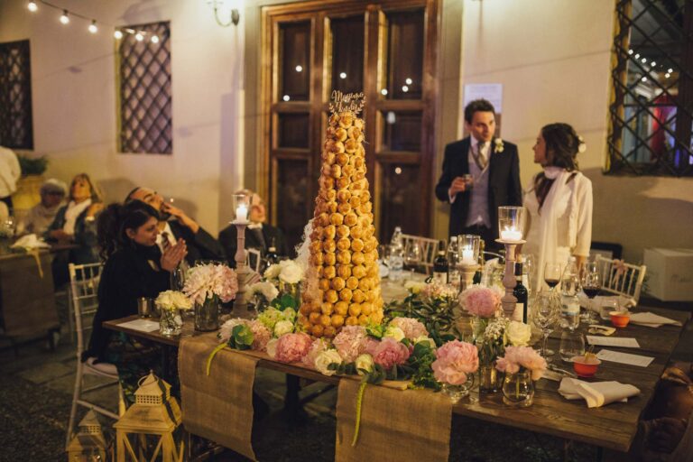 A croquembouche on a flower-dressed table under festoon lights, Tuscan DMC