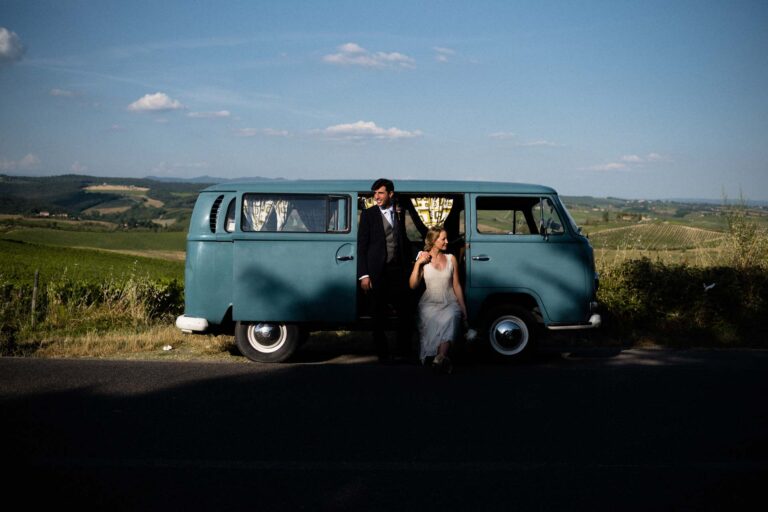 The couple with a vintage teal campervan, vineyards and hills behind, Tuscan DMC