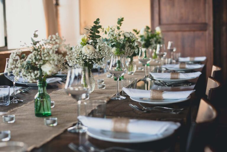 Tables dressed with gypsophila and greenery in glass bottles, hessian napkin ties, Tuscan DMC