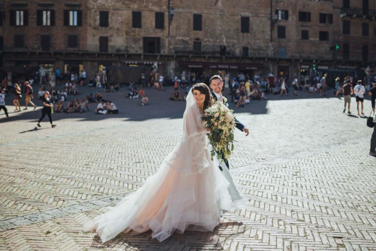 The bride crossing Piazza del Campo in Siena, bouquet in hand, Tuscan DMC