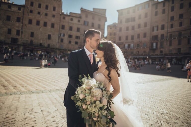 The couple in Piazza del Campo, Siena, the palazzi of the square behind them, Tuscan DMC