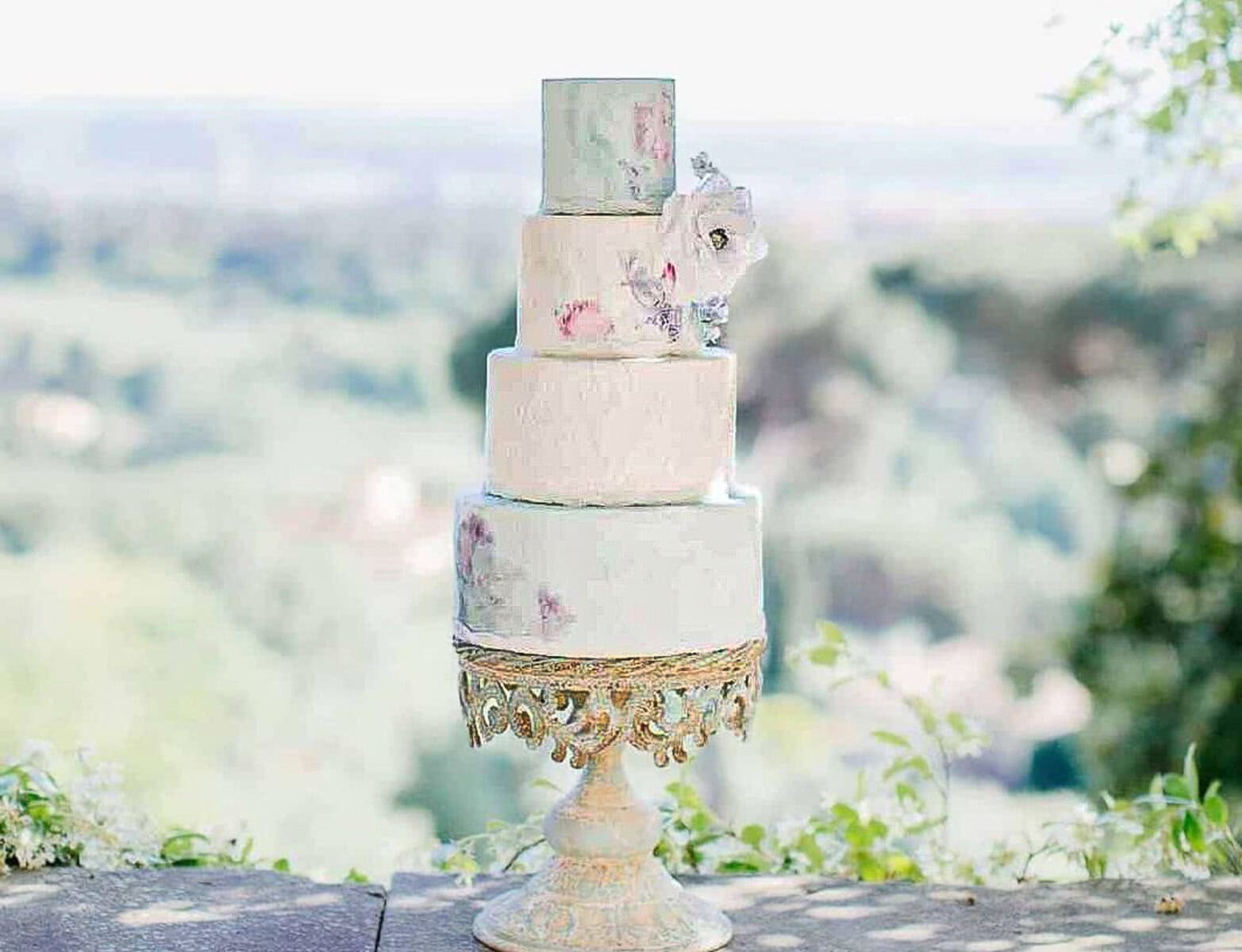 White tiered wedding cake with a watercolour blue and pink painted effect at Villa Fontanelle, Tuscany, Tuscan Wedding Cakes