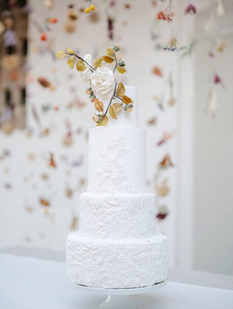 Four tier white wedding cake with sculpted bas-relief floral detail and a sugar rose topper, Italy, Tuscan Wedding Cakes