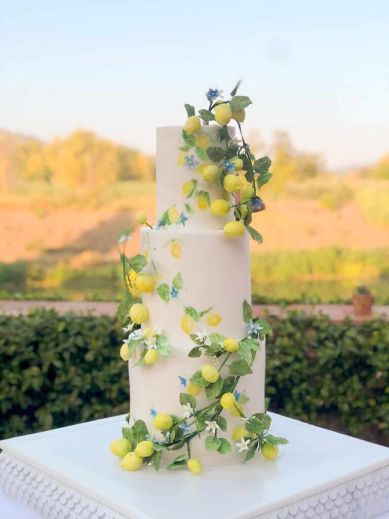 White tiered lemon wedding cake with cascading sugar lemons and greenery at Villa La Massa near Florence, Tuscany, Italy., Tuscan Wedding Cakes