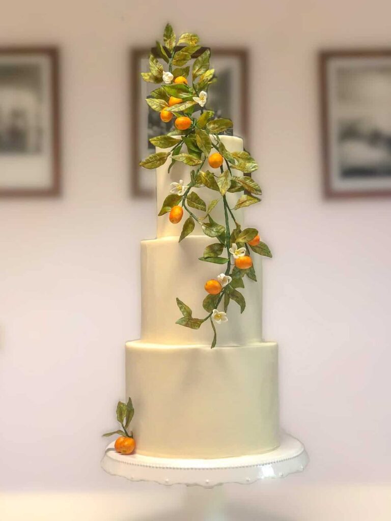 Tall white tiered wedding cake with cascading kumquats and citrus leaves at Hotel Il Pellicano in Porto Ercole, Italy., Tuscan Wedding Cakes