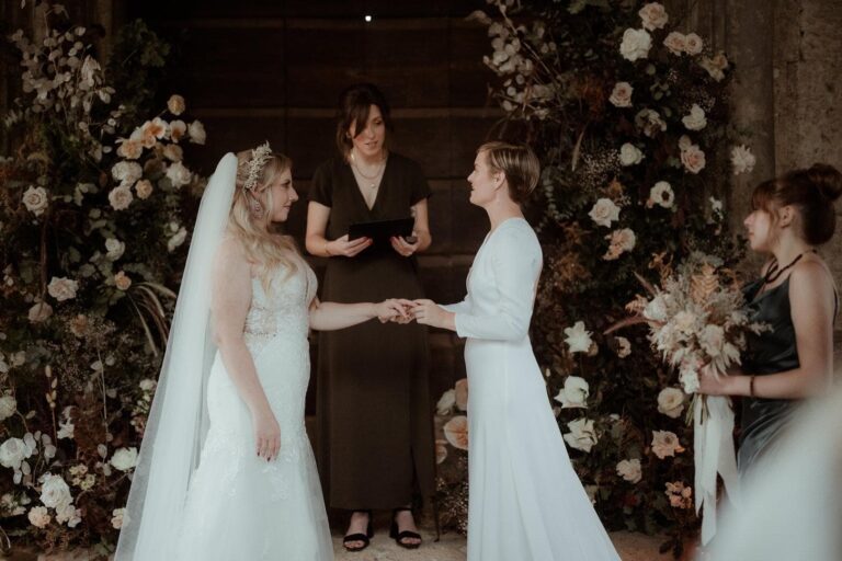 Two brides taking their vows in front of a wall of flowers, Umbria Weddings and Events
