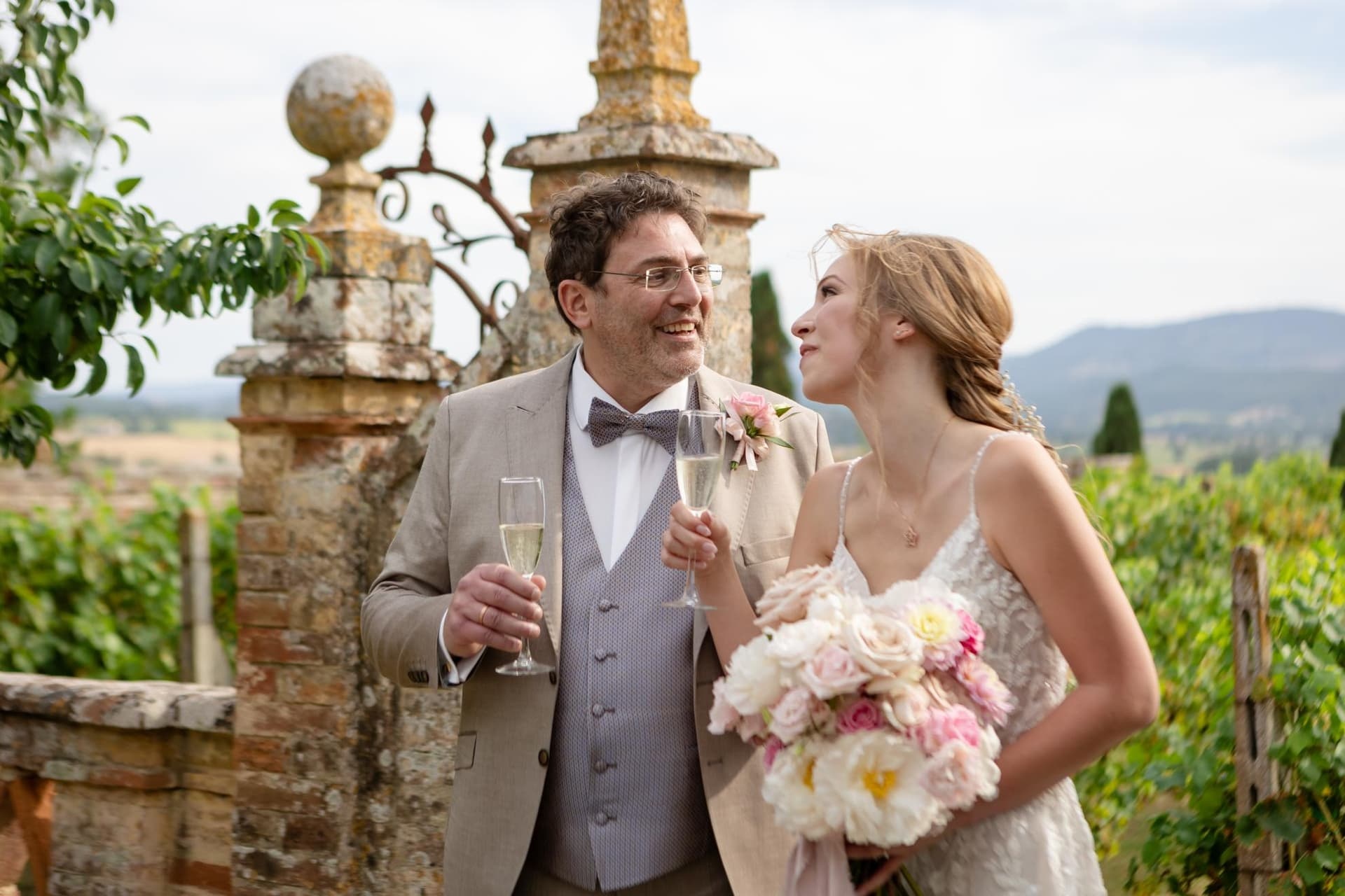 The toast at a stone gatepost, vines and the hills behind, Umbria Weddings and Events