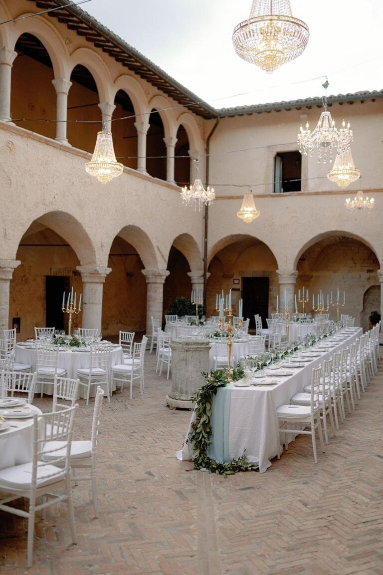 The abbey cloister laid for dinner under chandeliers, Umbria Weddings and Events