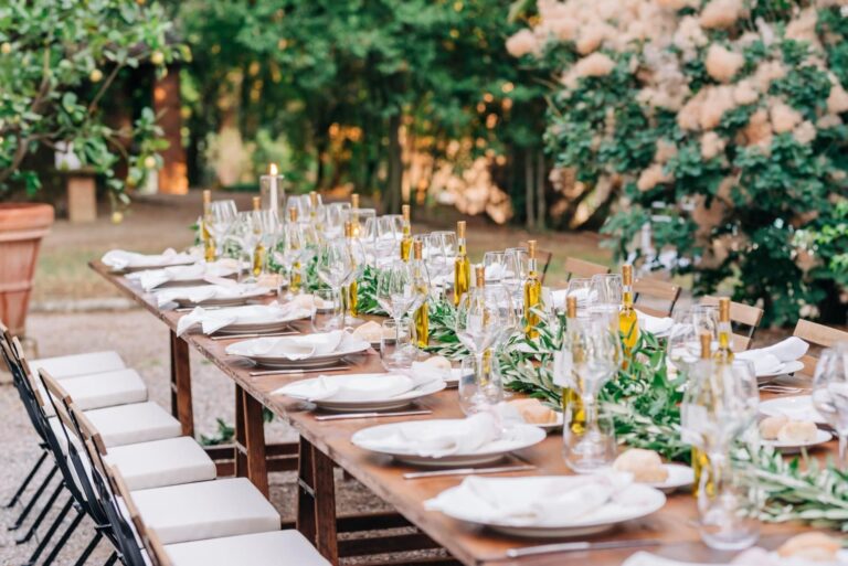 A long table under climbing roses, olive branches down the centre, Umbria Weddings and Events