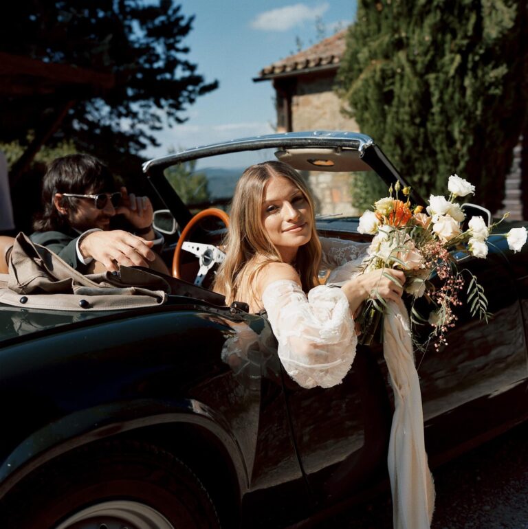 The bride in a vintage convertible, bouquet across the door, Umbria Weddings and Events