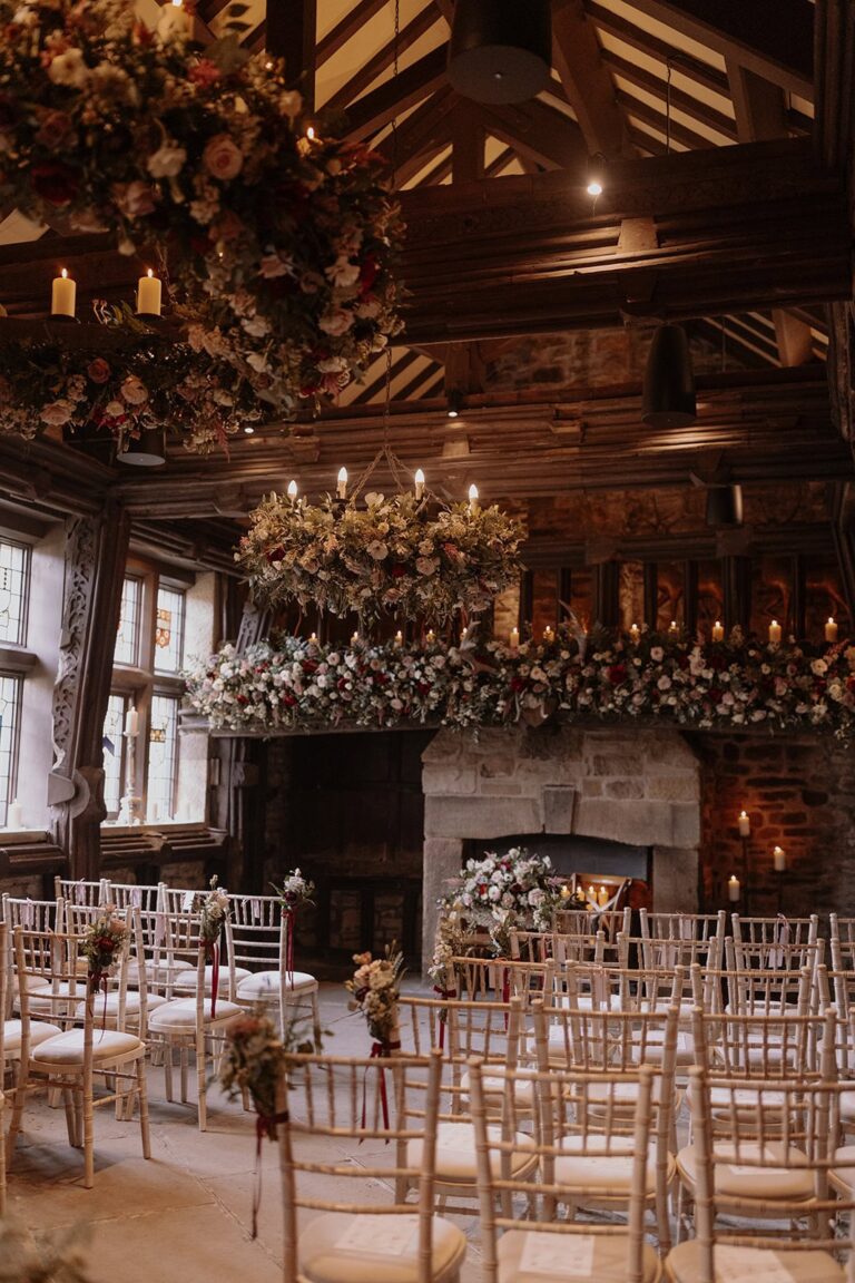 Chairs facing the fireplace in the Great Hall, under dried-flower hoops and a chandelier, Upper House Hayfield