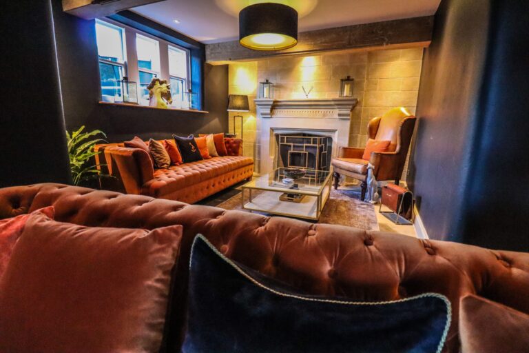 The Drawing Room, with velvet sofas, a stone fireplace and low lamplight, Upper House Hayfield