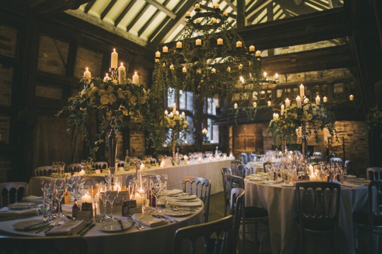 The Great Hall dressed with round tables, candles and tall floral arrangements, Upper House Hayfield