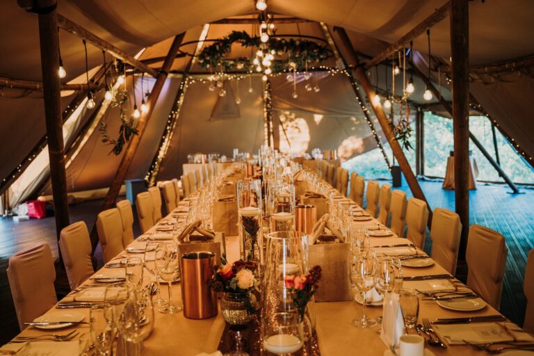 The Tipi Dining Hall laid with long tables, festoon lights and a picture window, Upper House Hayfield