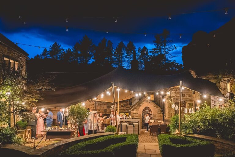 The castle courtyard at night under festoon lights and a stretch tent, Upper House Hayfield