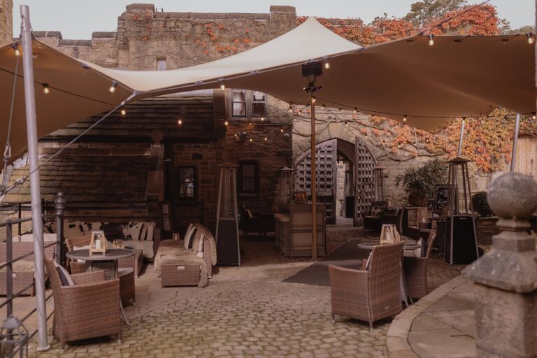 The covered courtyard lounge with rattan sofas, patio heaters and red ivy on the walls, Upper House Hayfield
