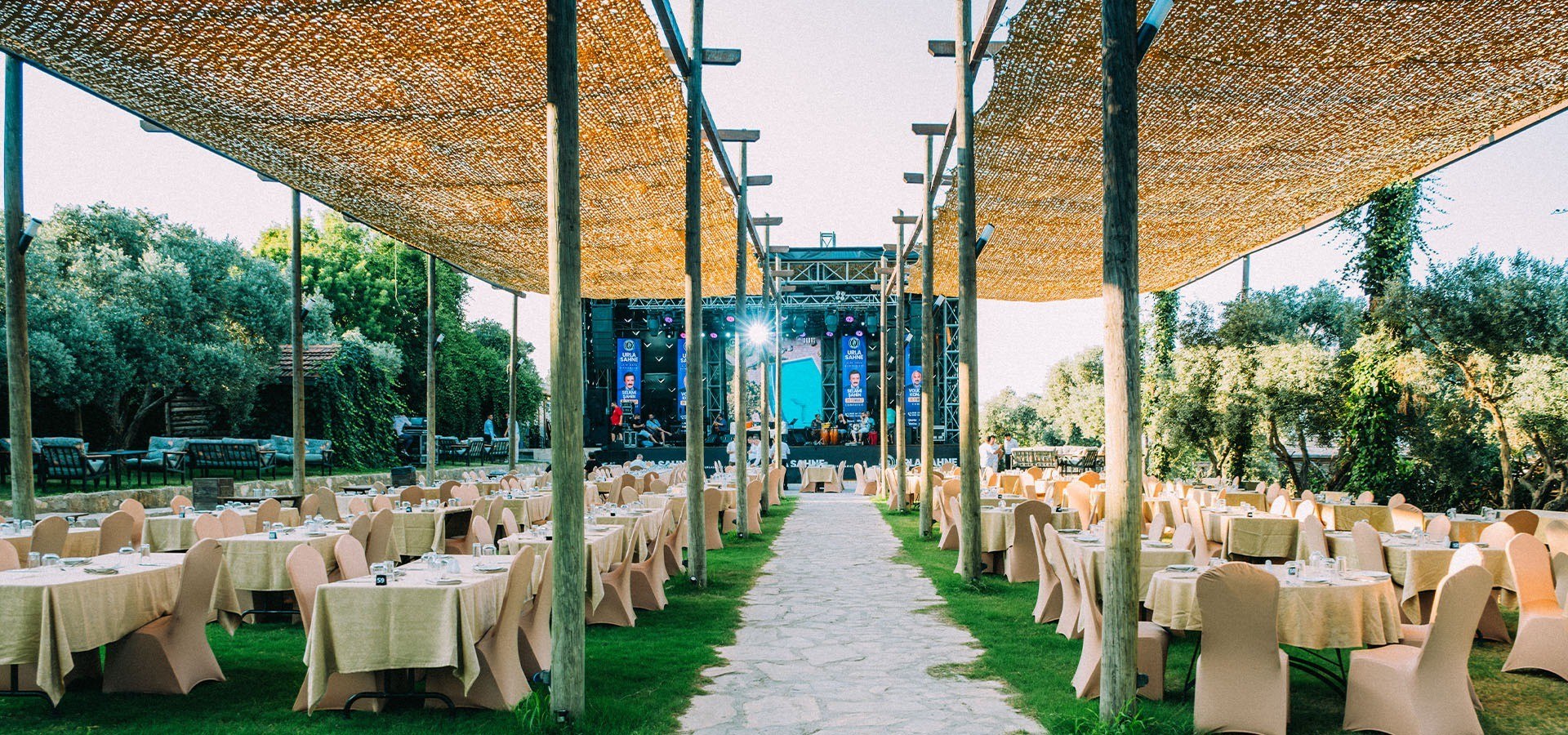 Rows of tables beneath a reed pergola facing the stage, Urla Sahne