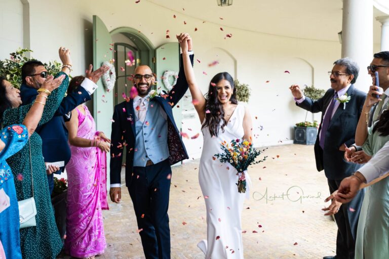 Petal confetti as a married couple walk out under the curved colonnade, Valentines Mansion & Gardens