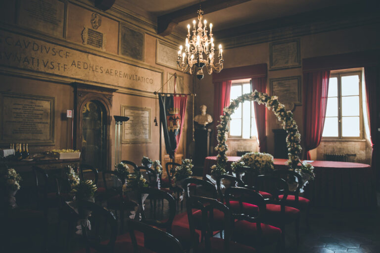 Civil ceremony hall in Rome with red chairs and a flower arch, Vera Weddings