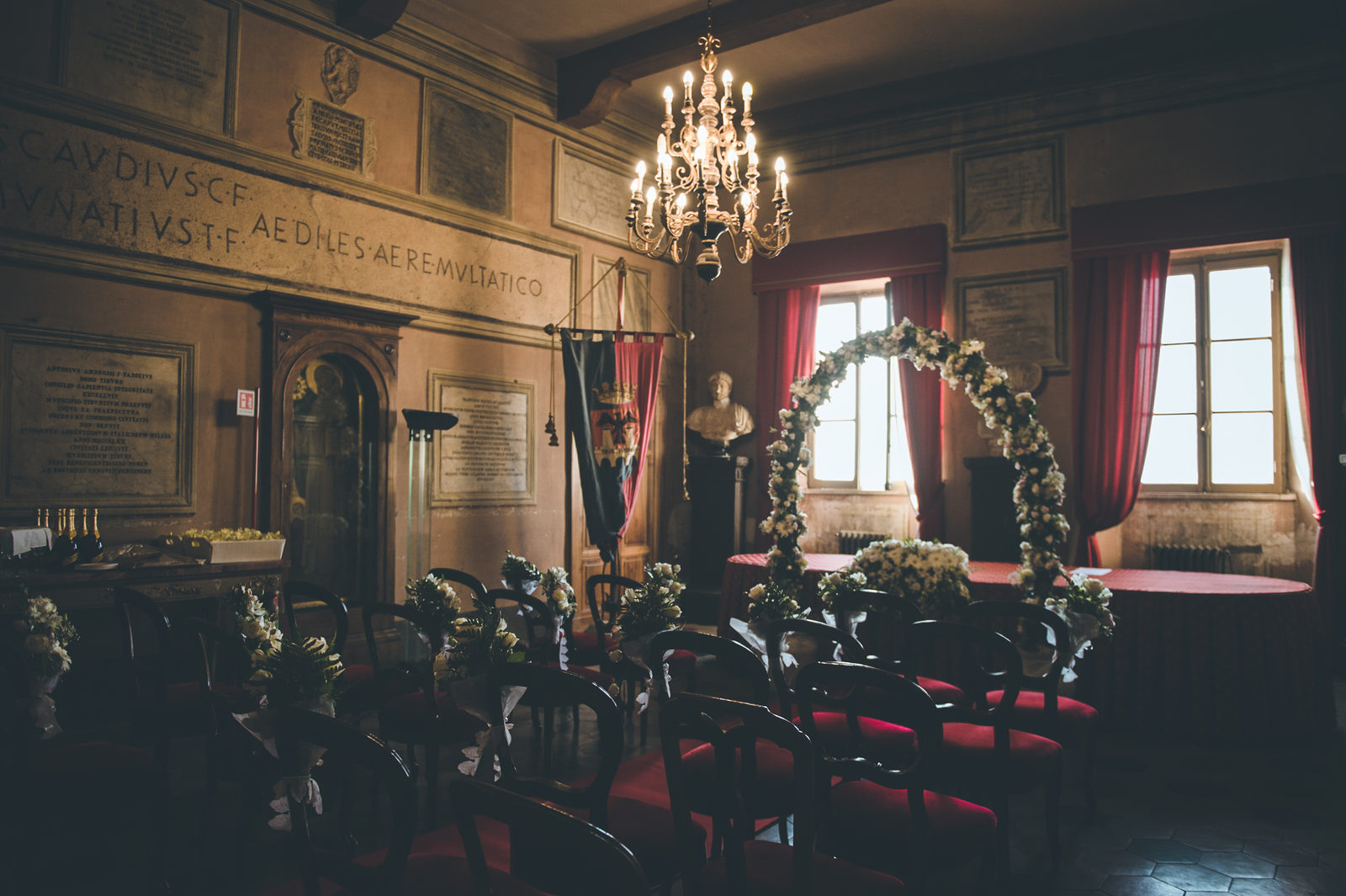 Civil ceremony hall in Rome with red chairs and a flower arch, Vera Weddings