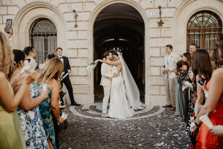 Couple walking through confetti under a stone archway in Rome, Vera Weddings