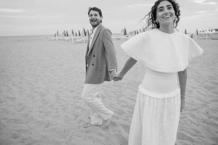 Couple walking hand in hand on a beach in Ostuni, black and white, Vera Weddings