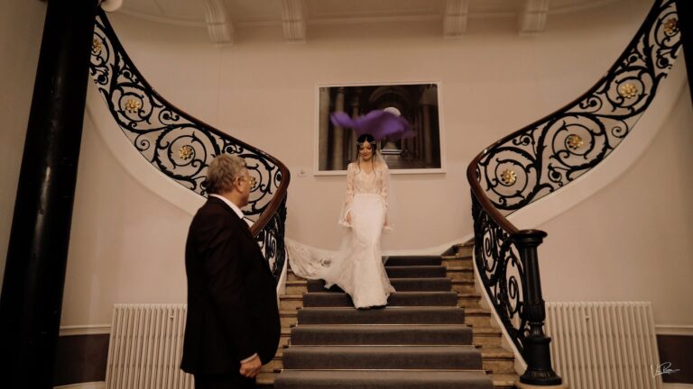 A bride coming down a curved staircase towards her father, from Nicole and James's highlights film, Vic Rivero Films