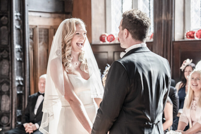 A laughing bride during the vows inside Adlington Hall, Cheshire, Victoria Amrose Photography