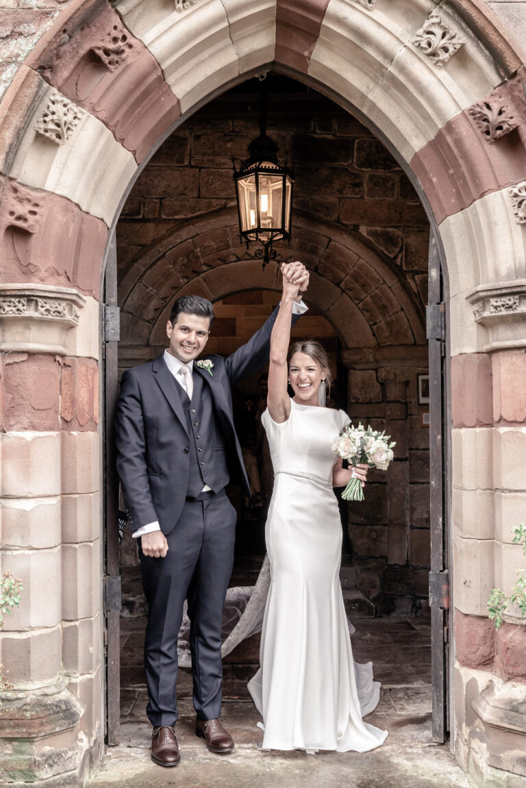 Newlyweds celebrating in a stone church doorway, for a wedding at Shooters Hill Hall, England, Victoria Amrose Photography
