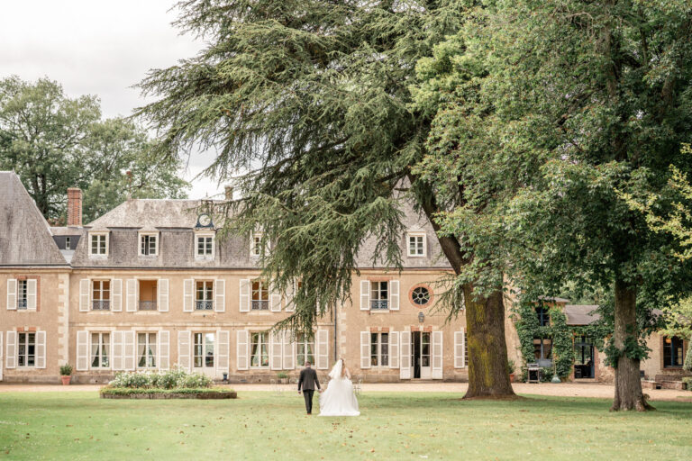 The couple walking across the lawn towards Chateau de Bouthonvilliers, France, Victoria Amrose Photography