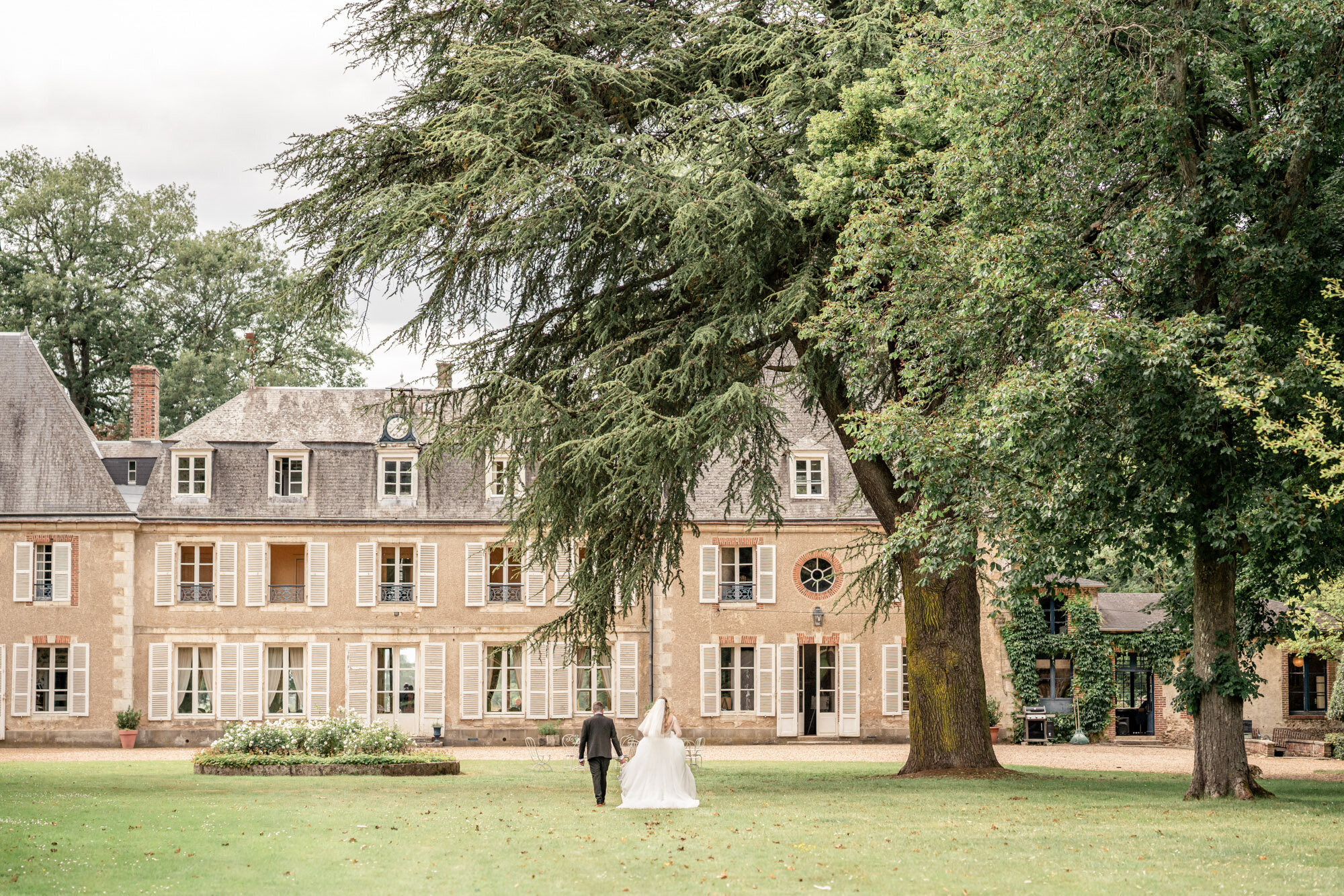 The couple walking across the lawn towards Chateau de Bouthonvilliers, France, Victoria Amrose Photography