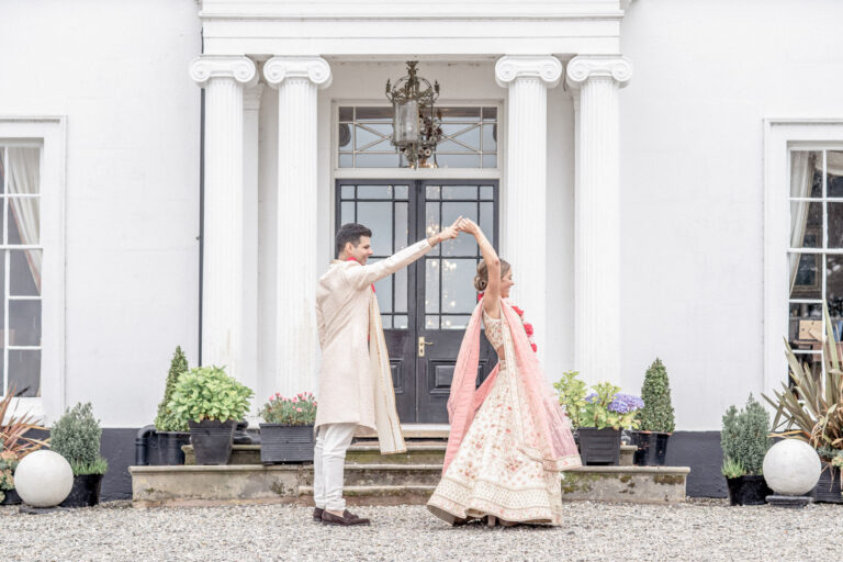 A dance under the portico in traditional Indian wedding dress, Shooters Hill Hall, England, Victoria Amrose Photography