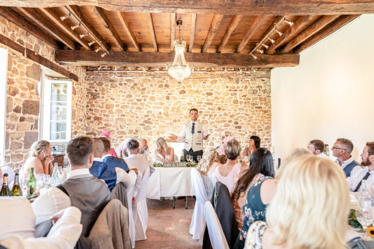 Speeches under the beamed ceiling of the stone reception room, Chateau du Grand Val, Brittany, France, Victoria Amrose Photography