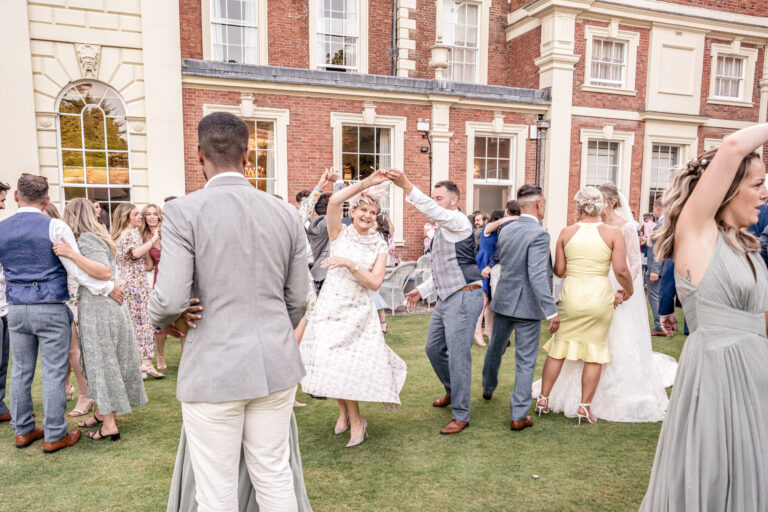 Guests dancing on the lawn in front of Hawkstone Hall, Shropshire, Victoria Amrose Photography