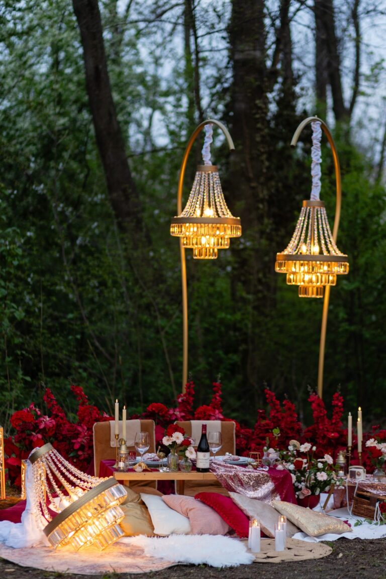Twin gold chandeliers above a red floral picnic in the woods, Vienna Picnics