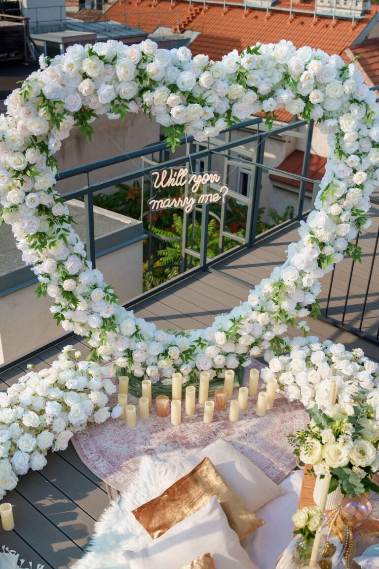 Heart-shaped white flower arch with a will you marry me neon on a city terrace, Vienna Picnics