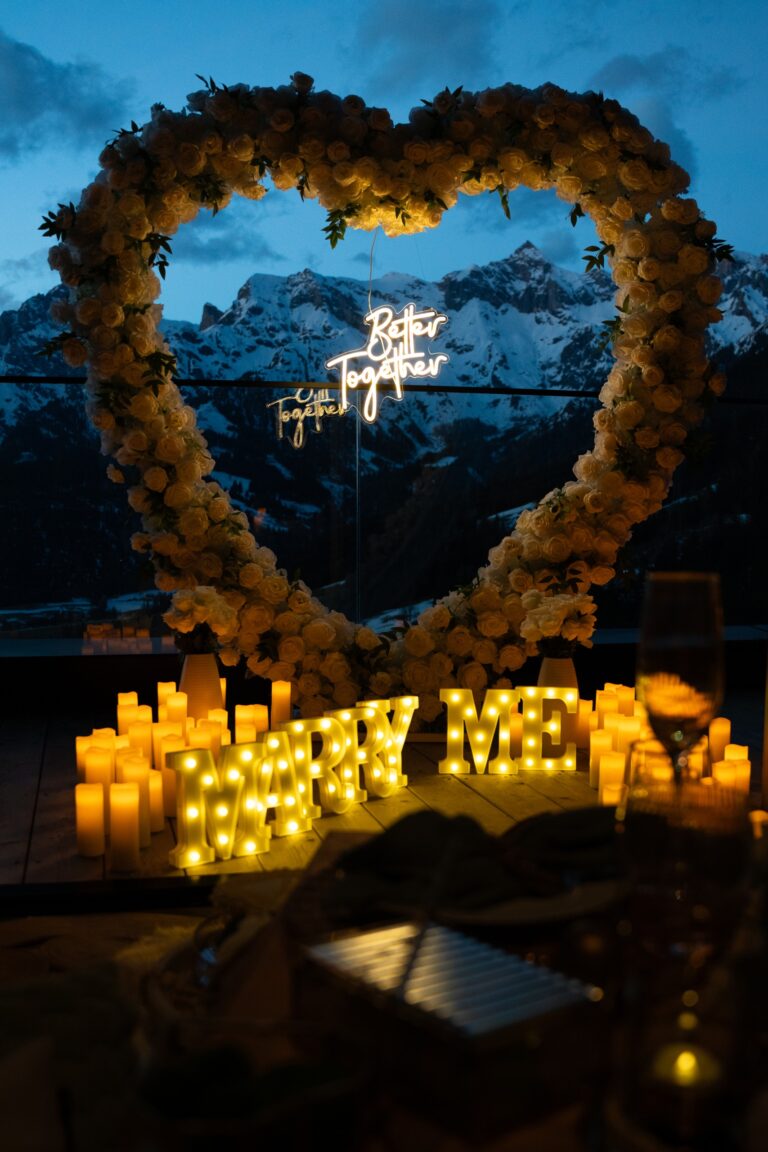 Illuminated heart arch with marry me letters and candles at dusk, mountains behind, Vienna Picnics